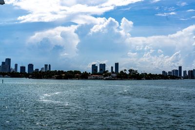 Sea by buildings against sky in city