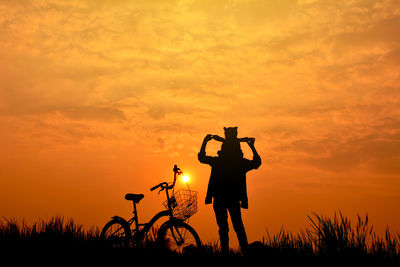 Silhouette of man with teddy bear on shoulders during sunset