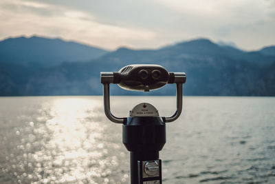 Coin-operated binoculars by sea against sky