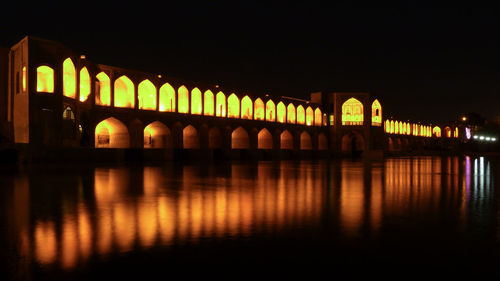 Illuminated bridge over river at night