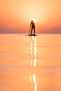 Silhouette man on beach against sky during sunset