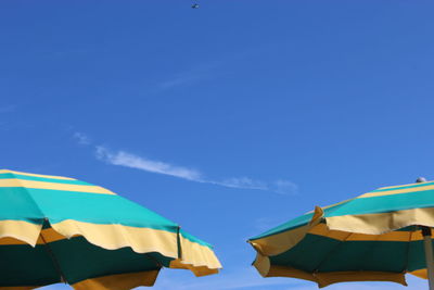 Low angle view of umbrellas against blue sky