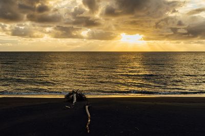 Silhouette man standing on beach against sky during sunset