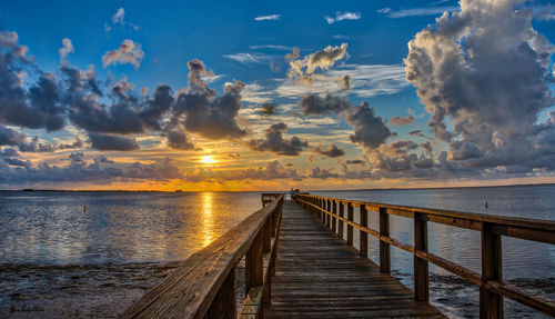 Pier over sea against sky during sunset