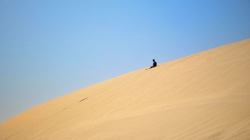Man on desert against clear blue sky