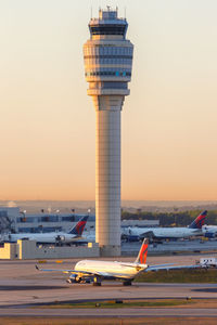 Airplane on airport runway against sky during sunset