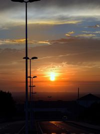 Street light against dramatic sky during sunset