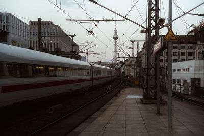 Train at railroad station in city against sky