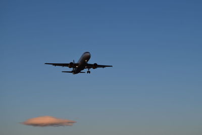 Low angle view of airplane against clear blue sky