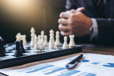 Midsection of businessman by chess board and document on table