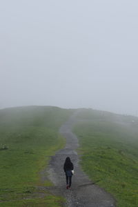 Rear view of woman walking on road during foggy weather