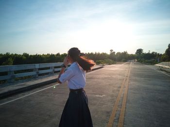 Woman standing on road against sky