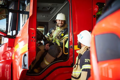 Firefighter talking with coworker while sitting in fire truck at fire station