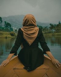 Rear view of woman sitting on rowboat in lake