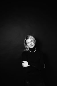 Portrait of a smiling young woman over black background