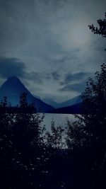 Scenic view of lake by silhouette mountains against sky