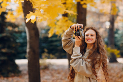 Portrait of young woman standing against trees