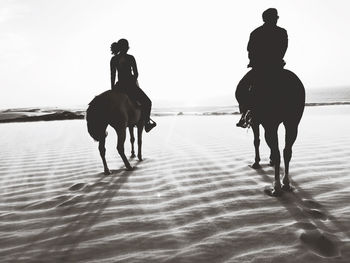 Silhouette people on beach against sky