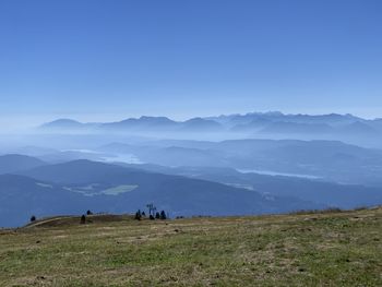 Scenic view of field and mountains against clear blue sky