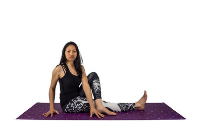 Portrait of young woman sitting against white background