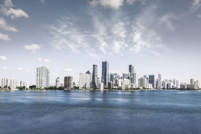 Sea by buildings against sky in city