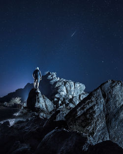 Man standing on rock against sky at night