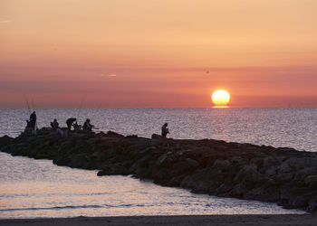 Silhouette people on beach during sunset