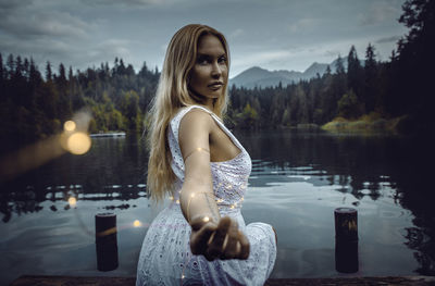 Portrait of woman standing by lake against mountain