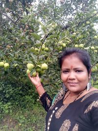 Portrait of young woman with fruits on tree