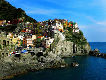 Buildings by sea against sky