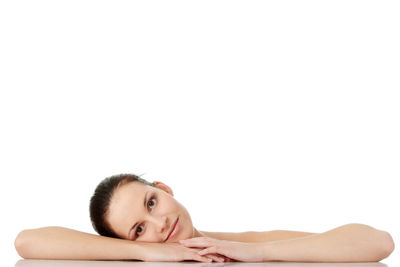 Portrait of young woman lying on white background