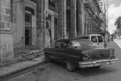 Abandoned car on street against buildings