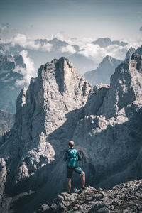 Man standing on rock by mountains against sky