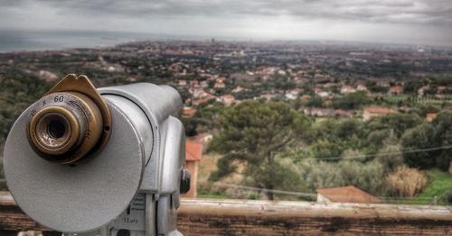 Close-up of coin-operated binoculars against cityscape