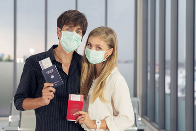 Life during covid-19 pandemic. young man and woman waiting for flying at airport at window