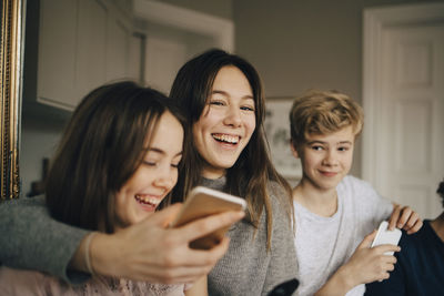 Close-up of cheerful friends with smart phones at home