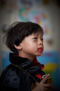 Close-up of cute boy with make-up and costume looking away