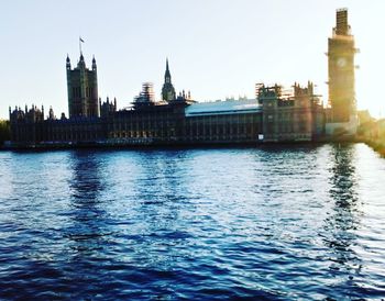 View of buildings by river against clear sky