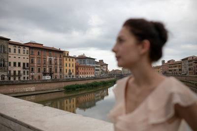 Woman standing against canal in city