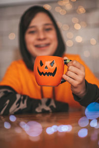 Portrait of young woman holding jack o lantern