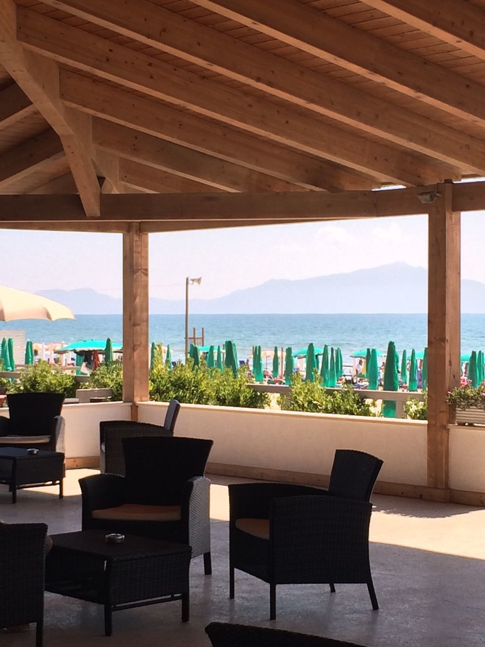 chair, table, empty, absence, restaurant, built structure, in a row, sky, bench, architecture, arrangement, sunlight, seat, lounge chair, shadow, day, sunshade, sea, beach, incidental people