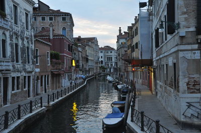 Canal amidst buildings in city against sky