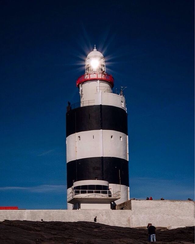 LOW ANGLE VIEW OF LIGHTHOUSE ON BEACH AGAINST BLUE SKY