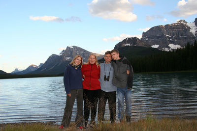 Portrait of family standing on lakeshore against mountains