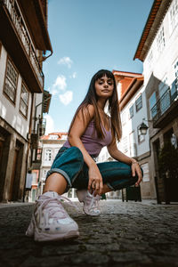 Portrait of smiling young woman against building in city