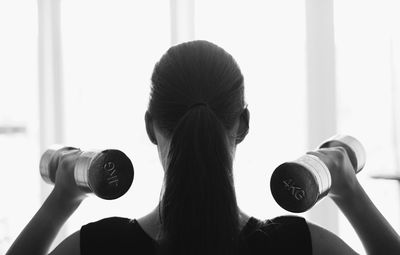 Rear view of woman holding dumbbells