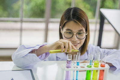 Scientist pouring chemical in test tube at laboratory