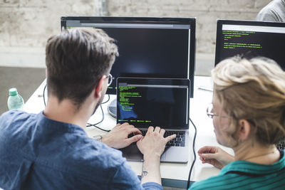 High angle view of computer programmers coding in laptop at desk