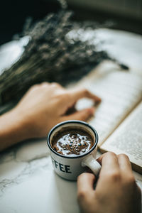 High angle view of woman holding coffee cup on table