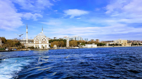 Buildings at waterfront against cloudy sky